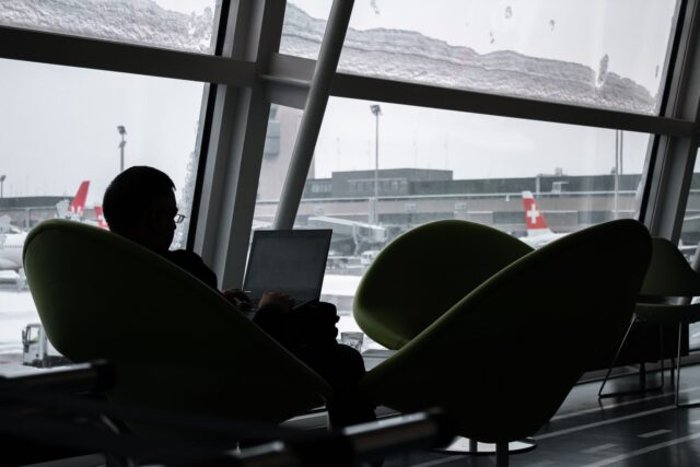 Laptop deschis pe o măsuță dintr-o sală de așteptare, conectat la rețeaua Wi-Fi publică a aeroportului