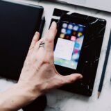 Telefon cu o aplicație de buget deschisă, așezat pe masă lângă câteva bonuri fiscale și un pix