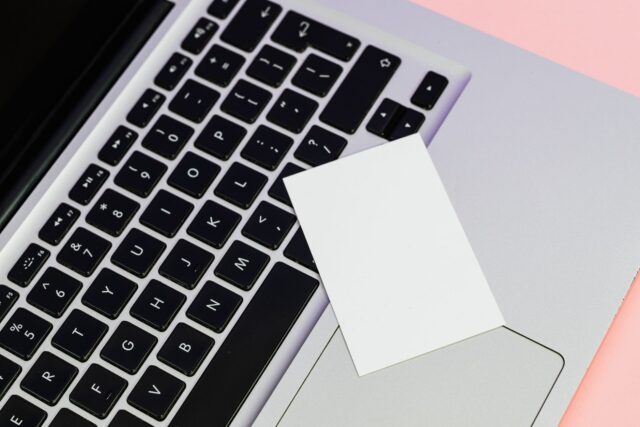 Tastatură de laptop curățată cu o pensulă moale, lângă o lavetă din microfibră și o șurubelniță mică