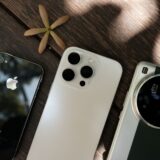 Mai multe smartphone-uri de dimensiuni diferite așezate unul lângă altul pe o masă din lemn