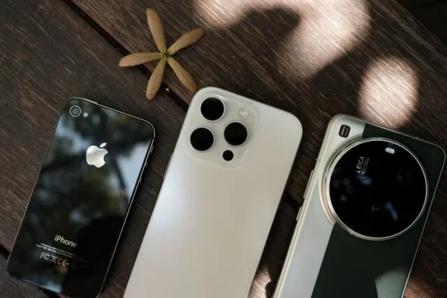 Mai multe smartphone-uri de dimensiuni diferite așezate unul lângă altul pe o masă din lemn
