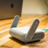 Router wireless cu antene, așezat pe un raft din sufragerie, cu leduri de funcționare aprinse