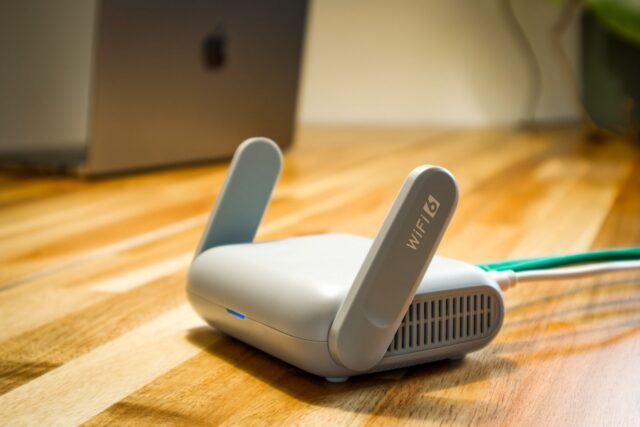 Router wireless cu antene, așezat pe un raft din sufragerie, cu leduri de funcționare aprinse
